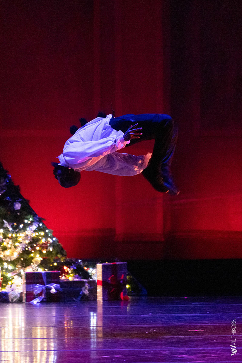 Dancer in a one-handed freeze under purple light